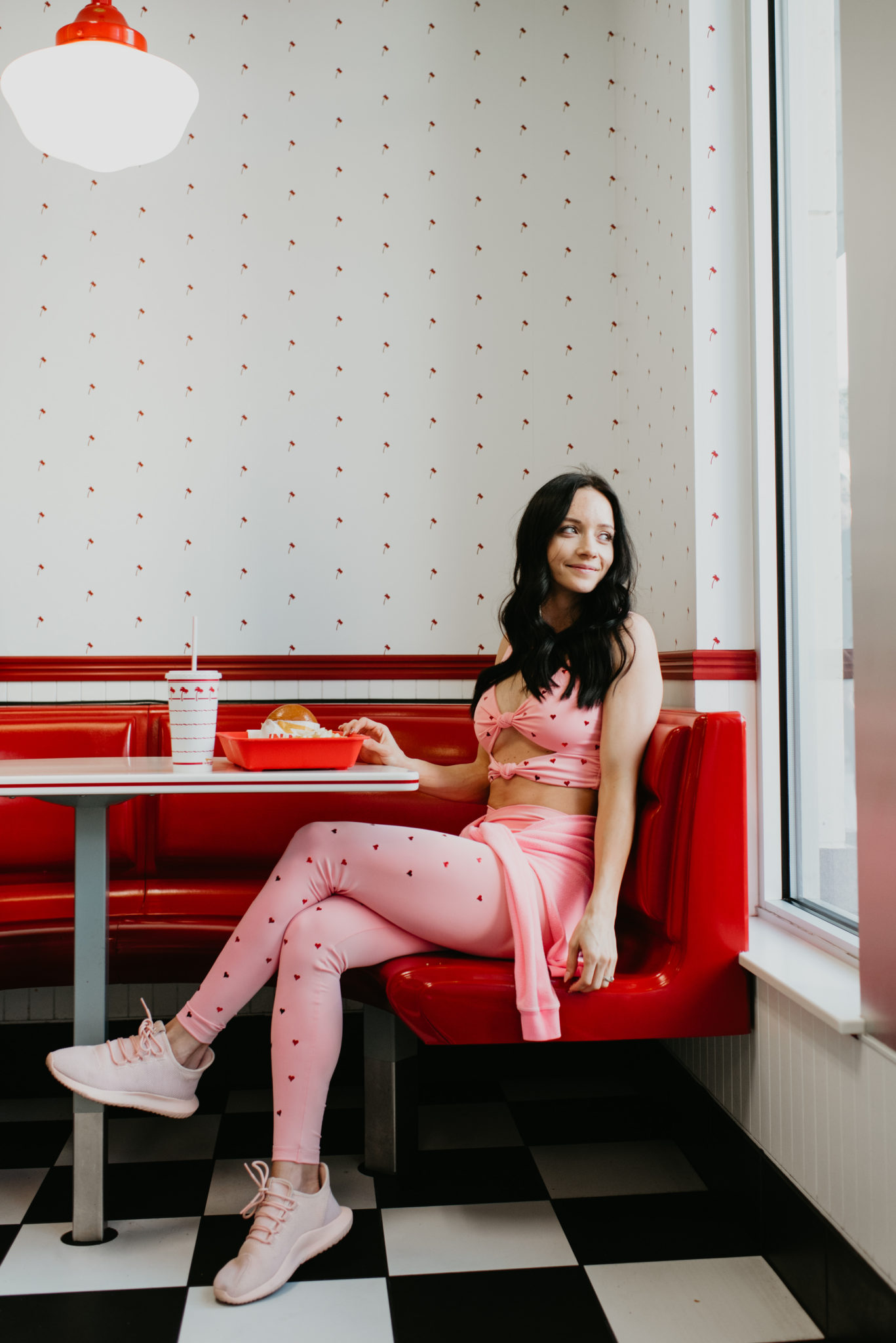 Cute Valentine's Inspired Pink Workout Clothes featured by top US fashion blog, Outfits & Outings: image of a woman wearing a Beach Riot pink sweatshirt, Beach Riot pink sports bra, Beach Rio pink metallic leggings and Adidas pink sneakers