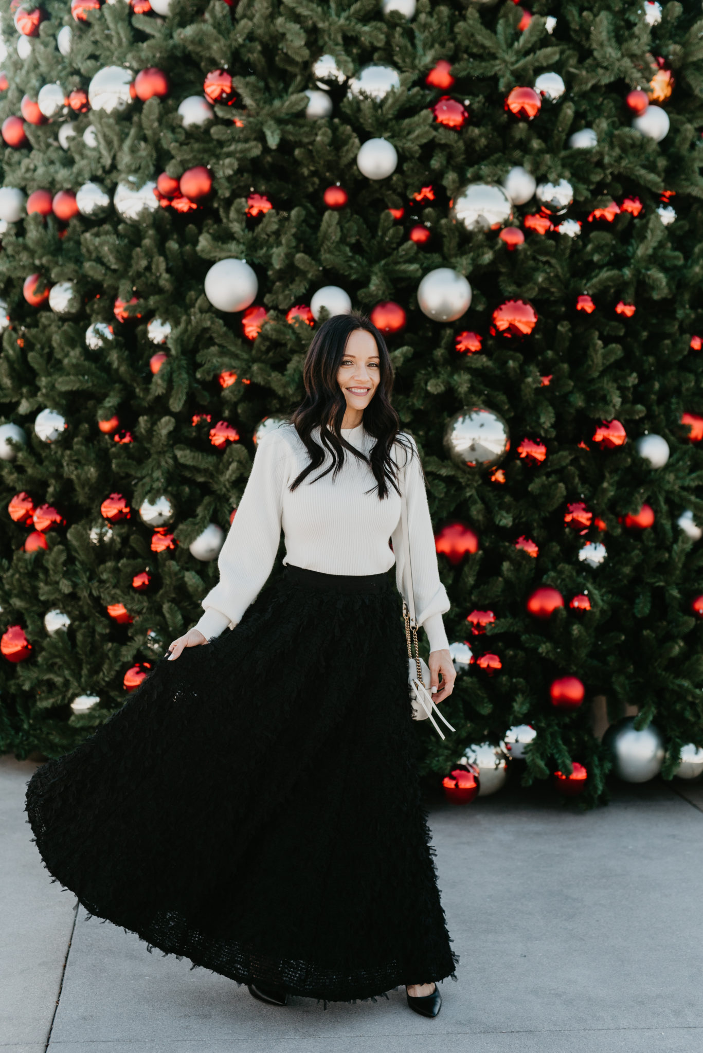 Festive Christmas Outfit Ideas featured by top US fashion blog, Outfits & Outings: image of a woman wearing an Anthropologie Feathered Maxi Skirt