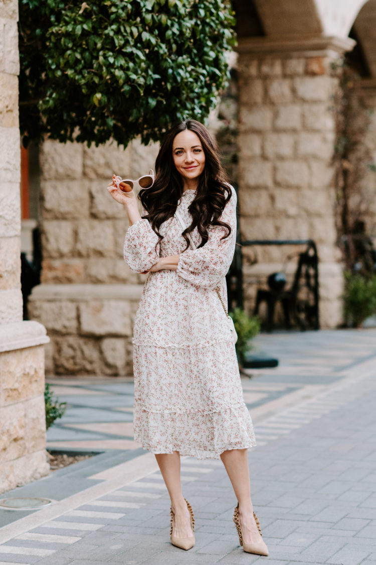 Wedding Guest Dresses by popular Las Vegas fashion blog, Outfits and Outings: image of a woman standing outside and wearing a white floral print dress and carrying a Gucci purse. 