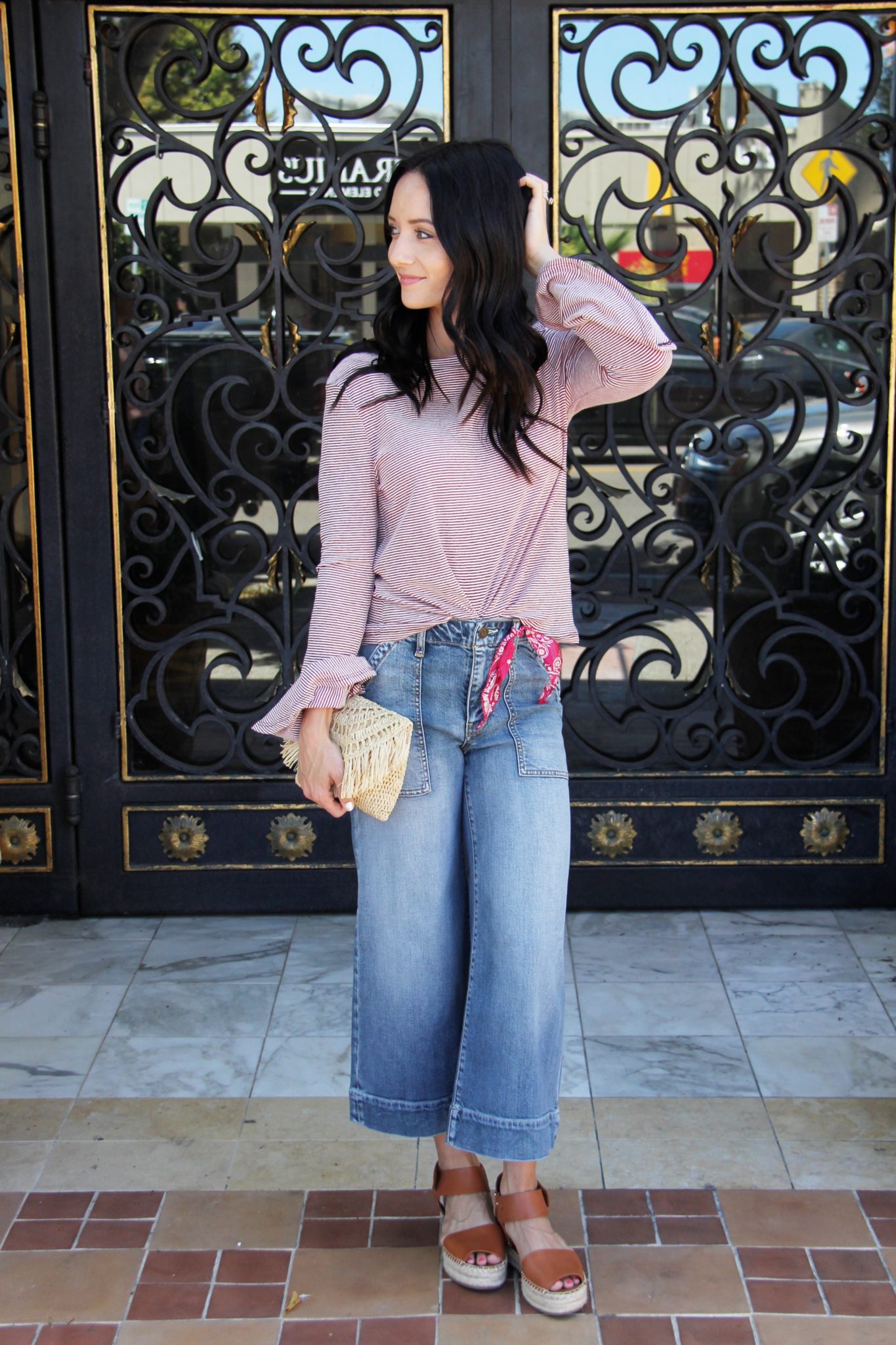 Cute Spring Outfits featured by top US fashion blog Outfits & Outings; Image of a woman wearing red top, wide leg jeans and sandals.
