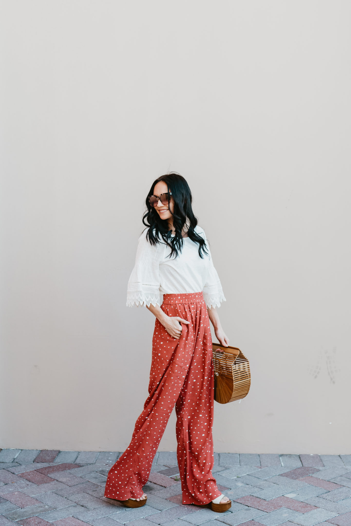 Bloggers Conference Packing List featured by top US fashion blog, Outfits and Outings: image of a woman wearing an Anthropologie eyelet top, Prima wide leg pants and Miuco bamboo handbag