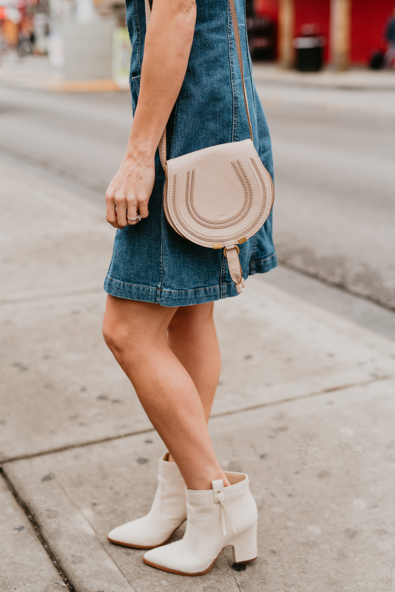 Cute Spring dress look styled by top US fashion blog, Outfits & Outings: image of a woman wearing a Madewell denim dress, Marc Fisher booties and a Chloe crossbody bag