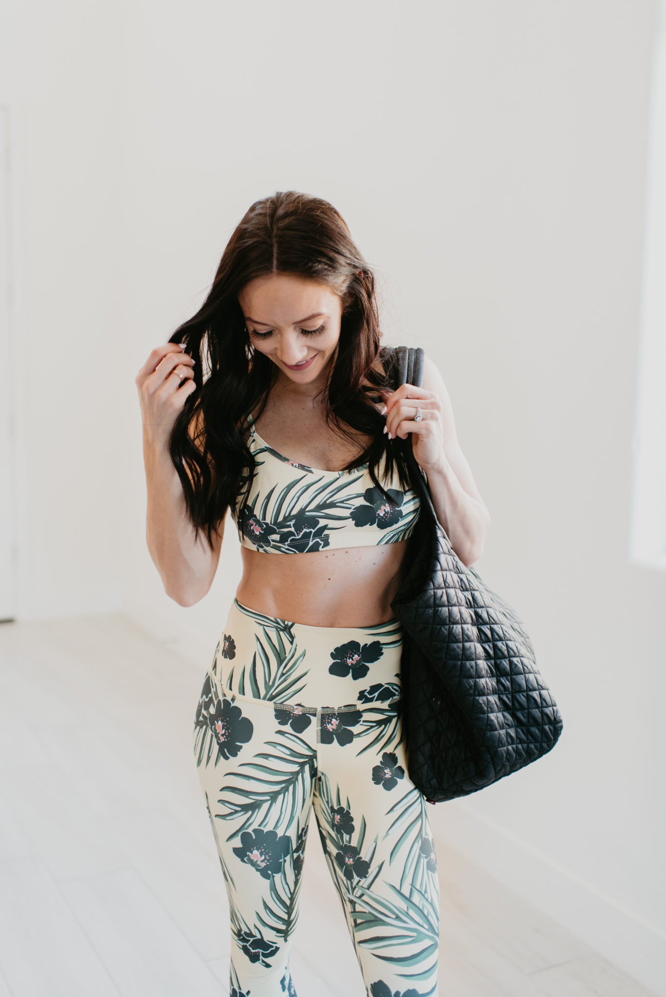 Cute Workout Sets for Spring featured by top US fashion blog, Outfits & Outings: image of a woman wearing a Beyond Yoga floral bra and leggings, MZ Wallace tote and Adidas UltraBoost sneakers