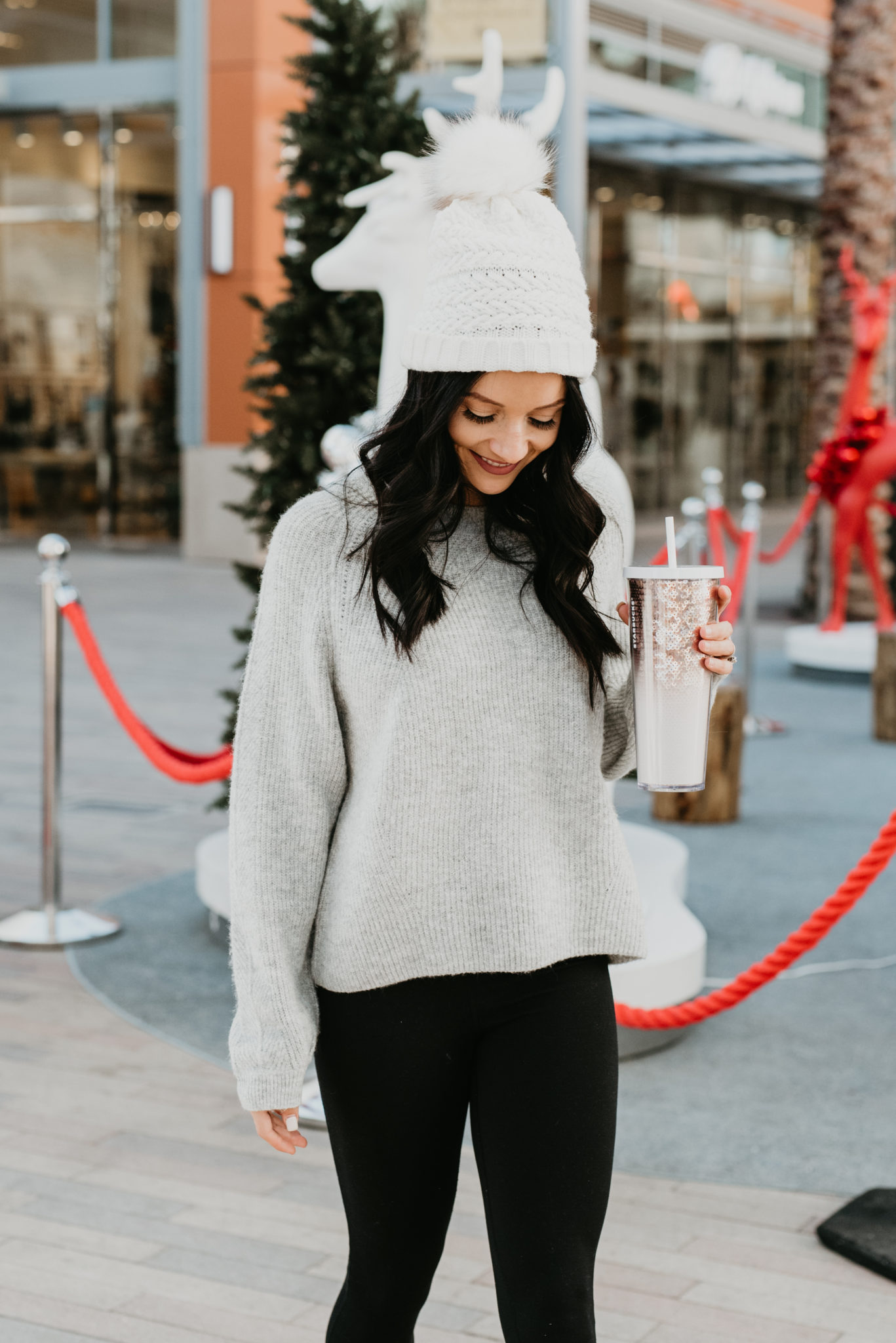 Festive Christmas Outfit Ideas featured by top US fashion blog, Outfits & Outings: image of a woman wearing a sweater, leggings and a pom pom hat