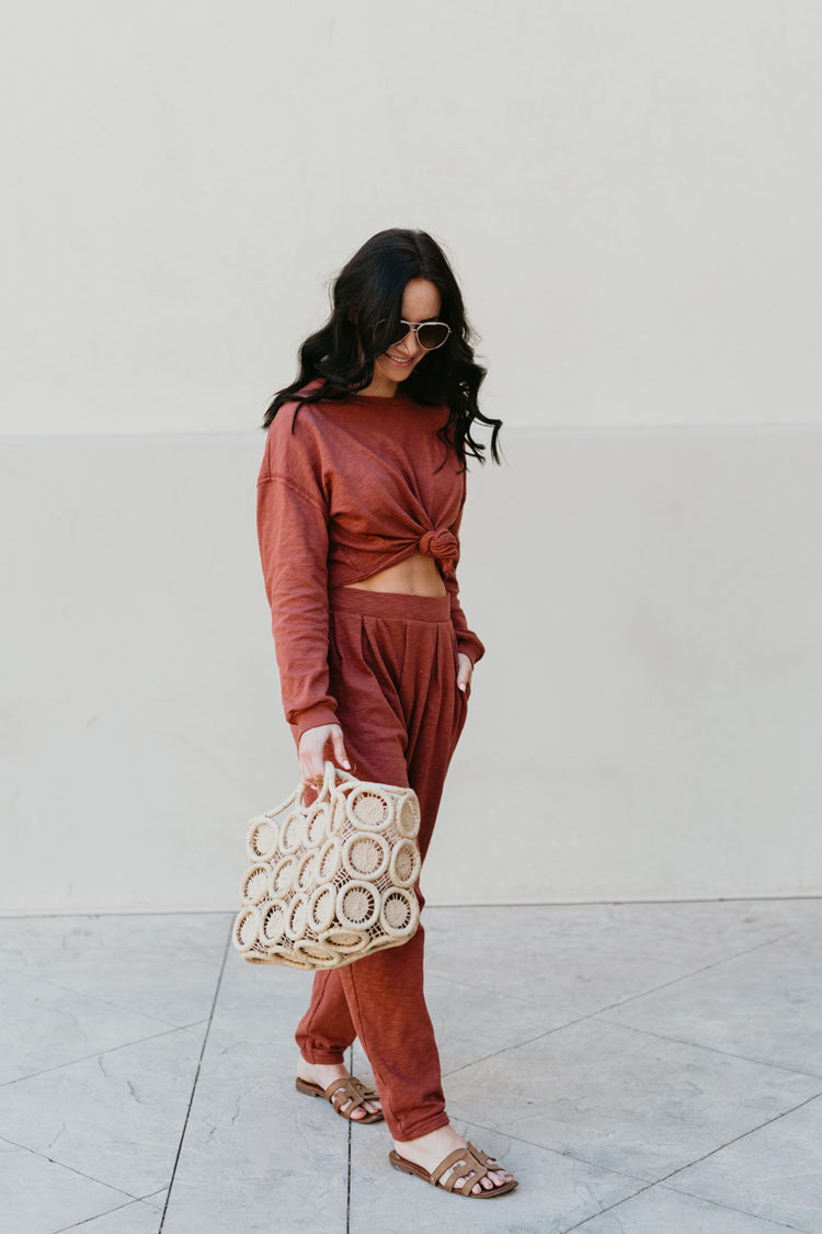 Matching Lounge Sets by popular Las Vegas fashion blog, Outfits and Outings: image of a woman wearing a red matching lounge set and holding a cream macrame bag. 