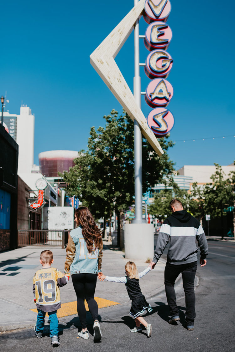 Golden Knights Gear by popular Las Vegas fashion blog, Outfits and Outings: image of a family walking across the street next to an old Vegas sign and wearing Golden Knights Gear. 