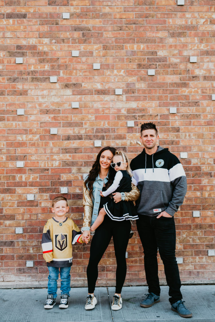 Golden Knights Gear by popular Las Vegas fashion blog, Outfits and Outings: image of a family standing in front of a brick wall and wearing Golden Knights gear. 