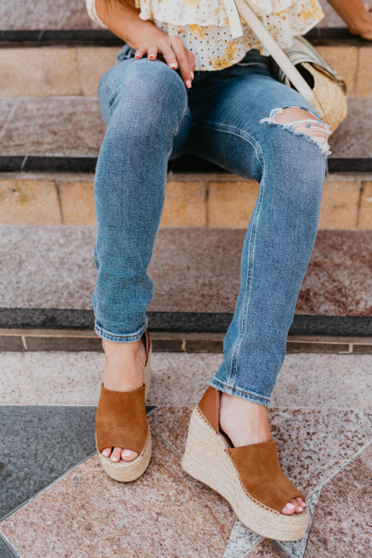 Eyelet Dresses by popular Las Vegas fashion blog, Outfits and Outings: image of a woman sitting on some stone steps and wearing a white and yellow eyelet top distressed and a pair of espadrilles. 