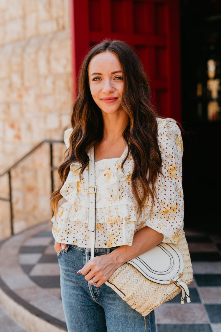 Eyelet Dresses by popular Las Vegas fashion blog, Outfits and Outings: image of a woman walking out of the doorway of a restaurant with a red door and wearing a white and yellow eyelet top distressed and a pair of espadrilles. 